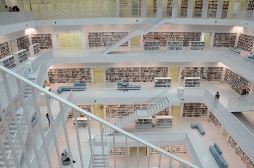 Free Contemporary library interior featuring white staircases and bookshelves, showcasing modern architecture. Stock Photo