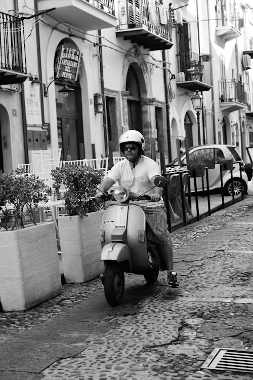 Man Riding Motor Scooter in Black and White