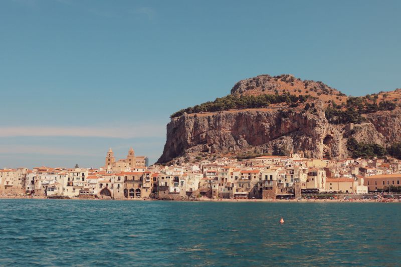 Explore the stunning seaside architecture of Cefalù, Sicily, with rocky backdrops and historic charm.