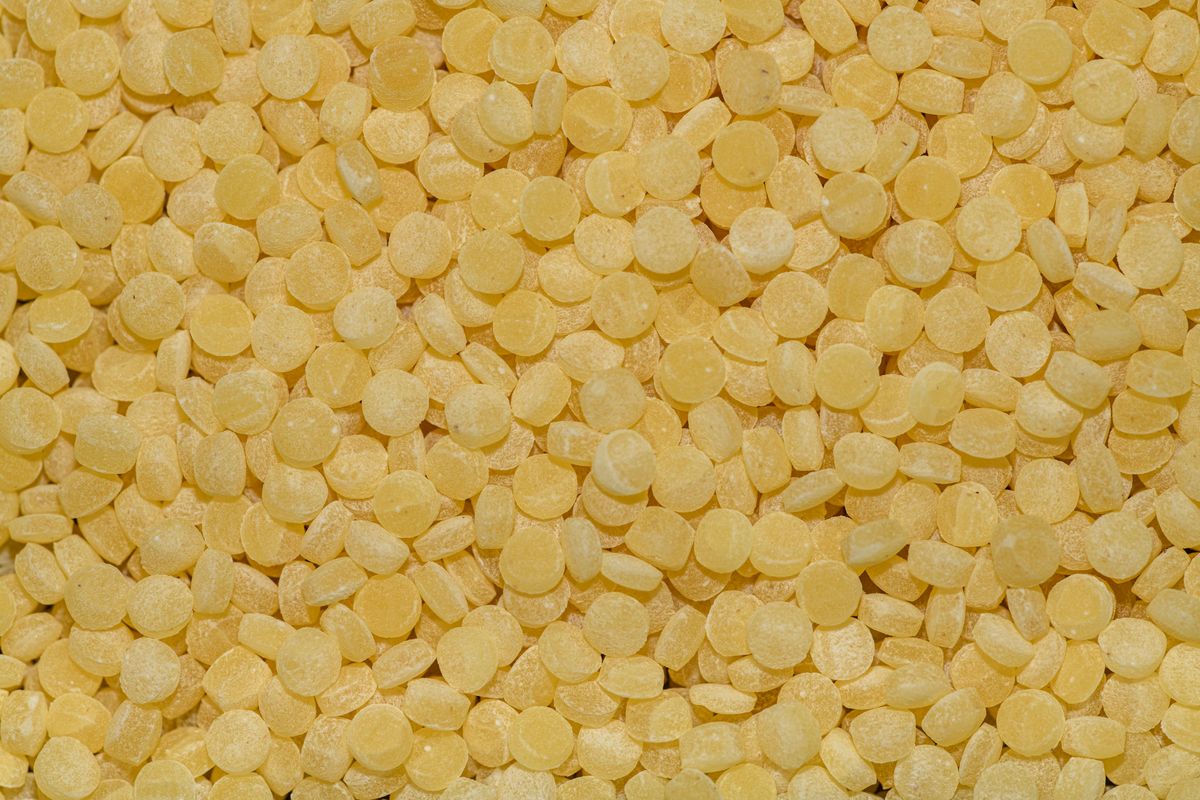 Macro shot of an abundance of yellow candies, closely packed and stacked.