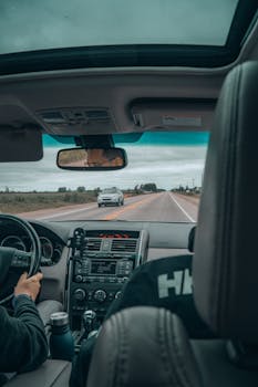 Interior view of a car driving down a scenic road with two passengers capturing a travel journey.