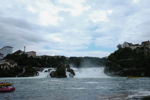 Free Breathtaking view of Rhine Falls in Switzerland with colorful tour boats under cloudy skies. Stock Photo
