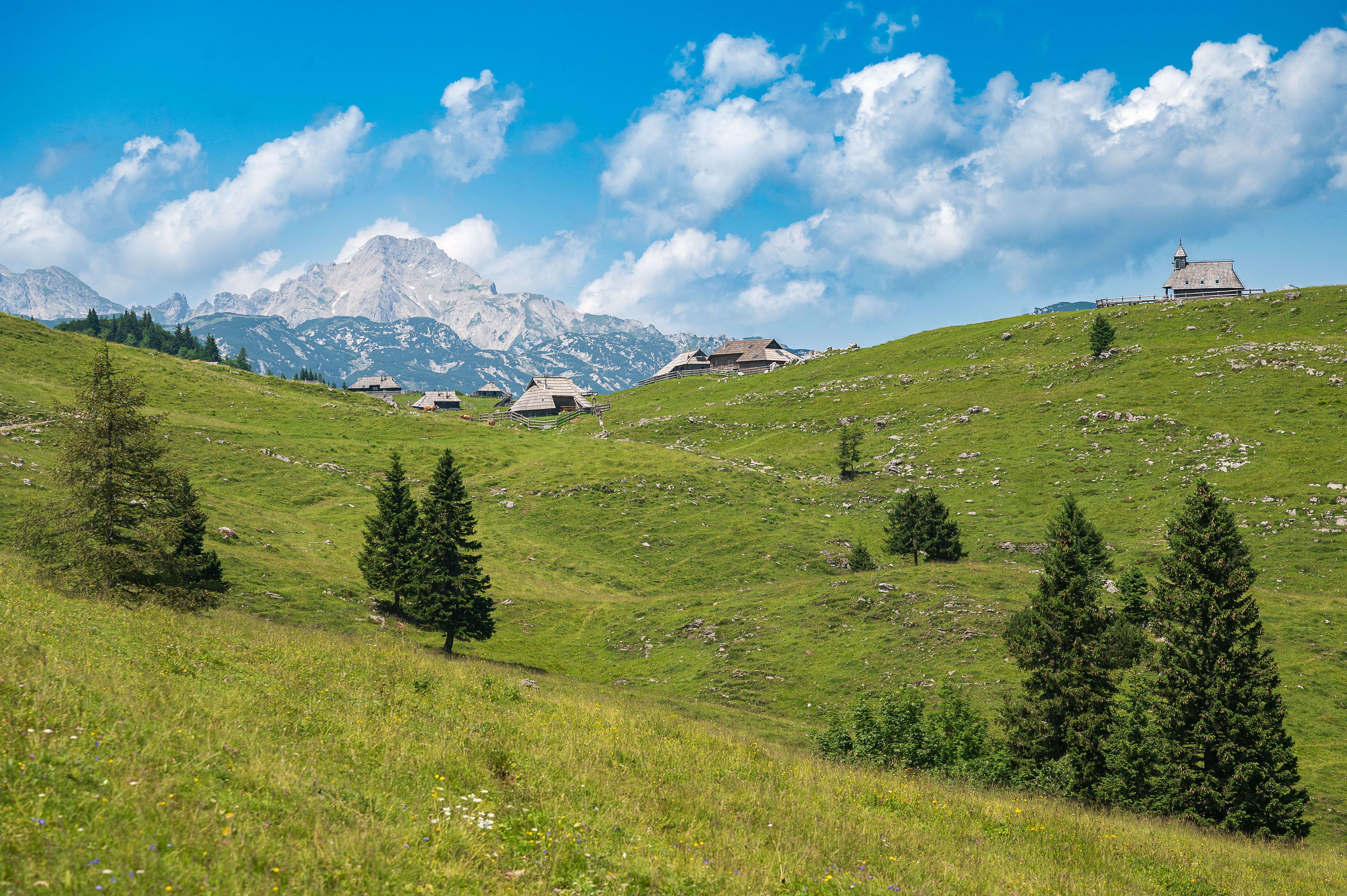 Idyllic village in Stahovica, Slovenia with green hills and mountain backdrop in summer.
