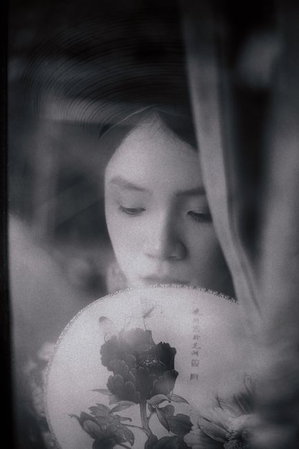 Artistic black and white portrait of a woman with a floral fan.