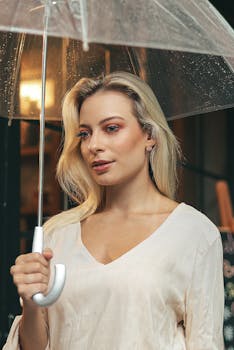 雨中，一位金发时尚的年轻女子撑着一把透明伞