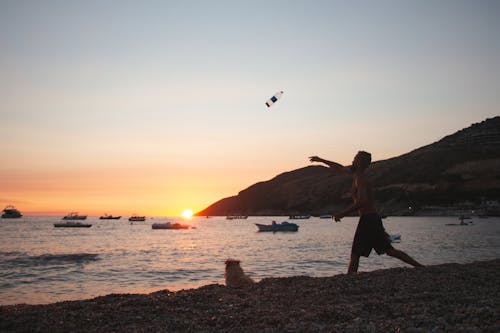 Man Throwing Bottle to Sea at Sunset