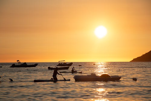 People and Motorboats on Sea Coast at Sunset