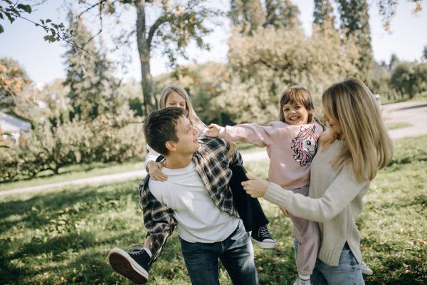 Parents playing with two children in a park, photo by Katerina Kolomina on Pexels