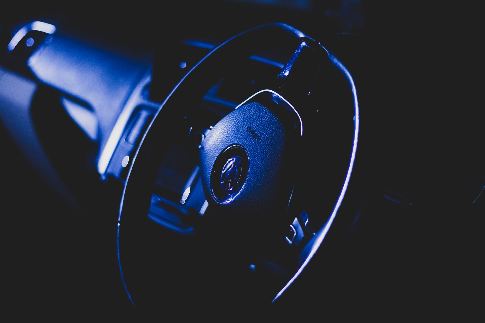 Artistic dark photo highlighting a car steering wheel and dashboard details.