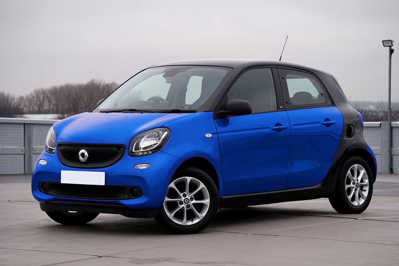 A sleek blue compact car parked outdoors in an urban setting