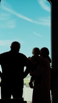 A family's silhouette against a bright airport window, suggesting travel and anticipation.