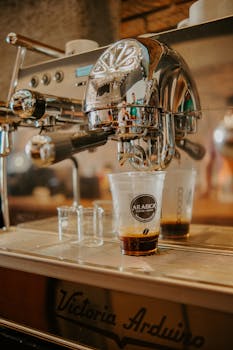A Victoria Arduino espresso machine pouring fresh coffee into a cup in a café setting.