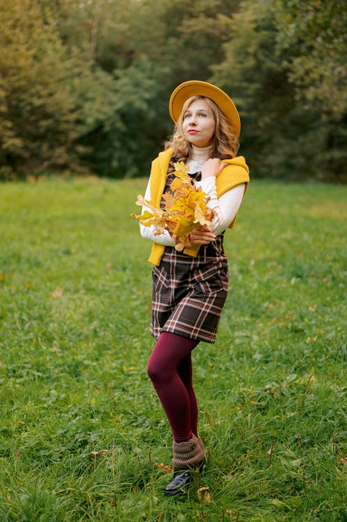 Blonde Woman in Dress Posing with Fallen Leaves on Grassland