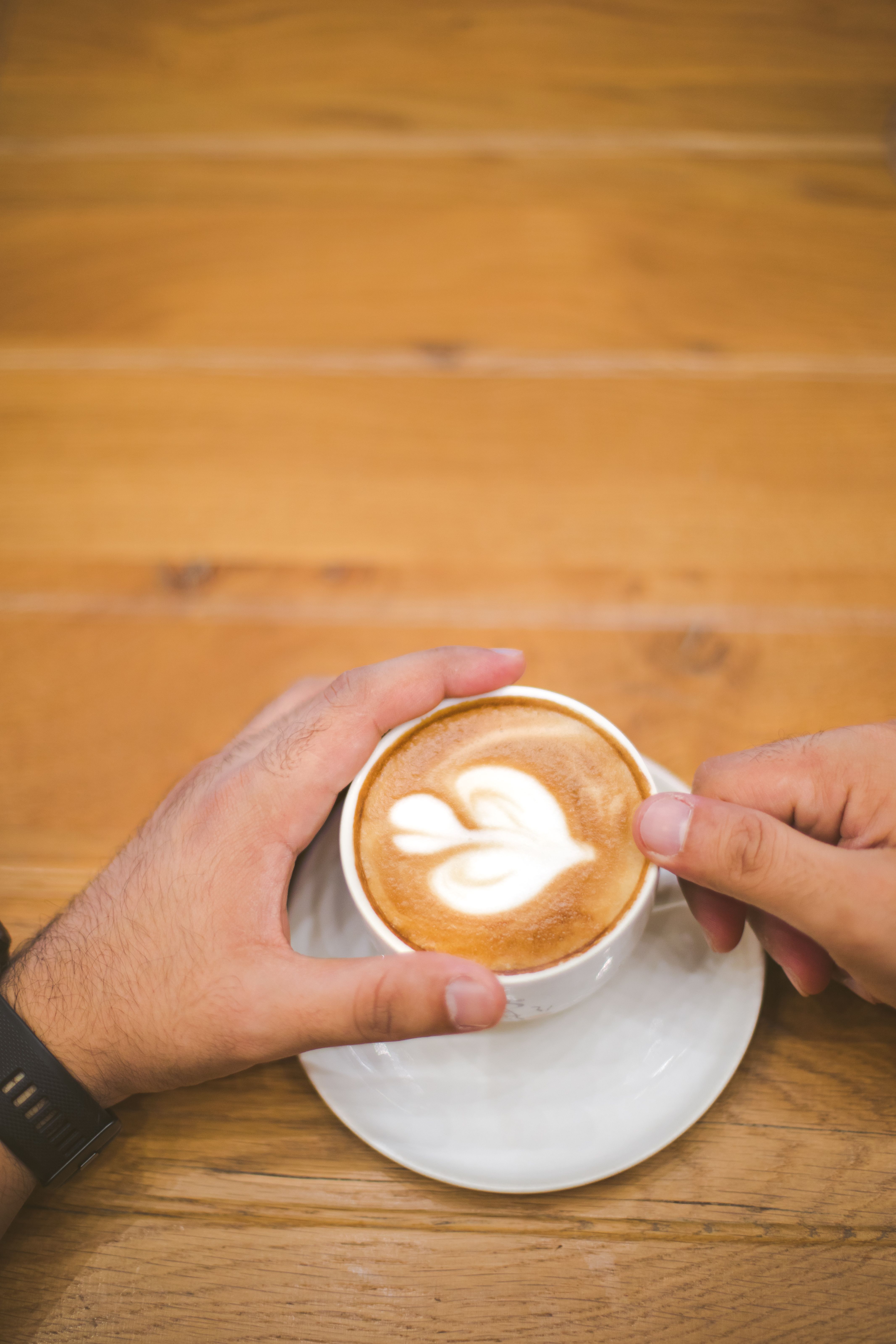 Top view of latte art with two hands holding the cup indoors.. view, latte, with