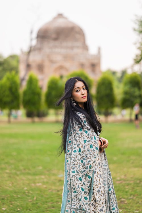 Young Woman Posing on Lawn near Traditional Building