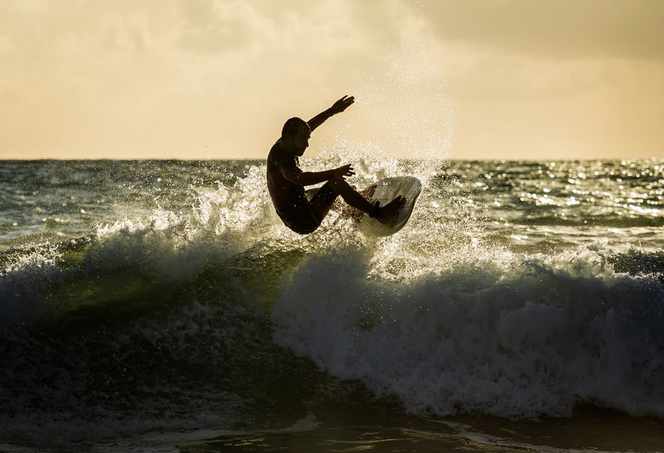 A dynamic shot of a surfer skillfully riding a wave against a stunning sunset backdrop.