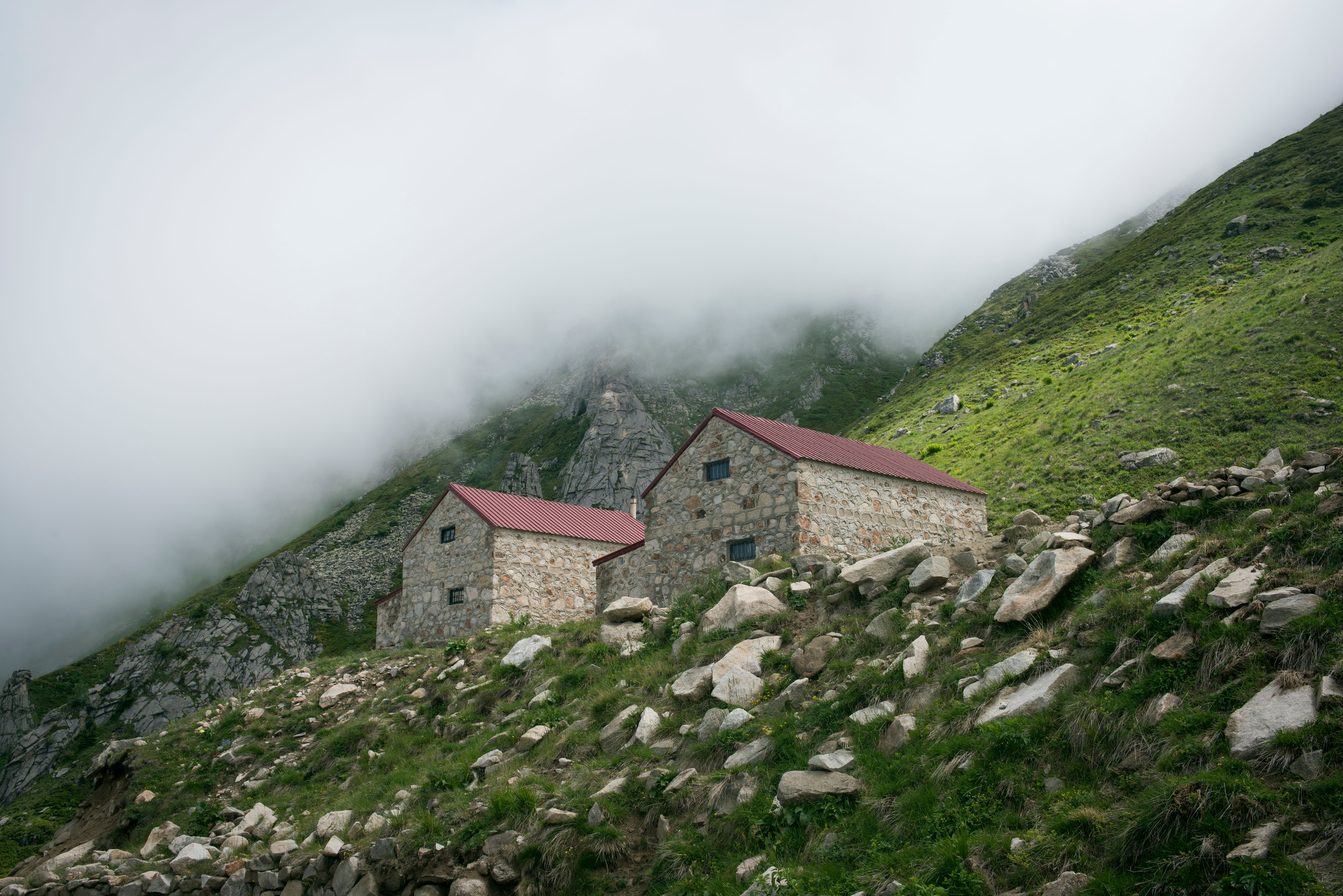Fog rolling over a small Alpine village, a single lit window in a stone house