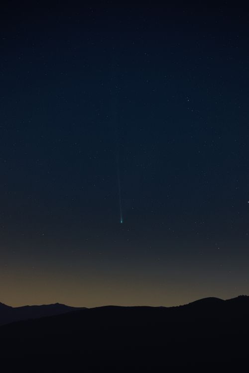 Free Starry night sky with a shooting star above mountain silhouette. Stock Photo