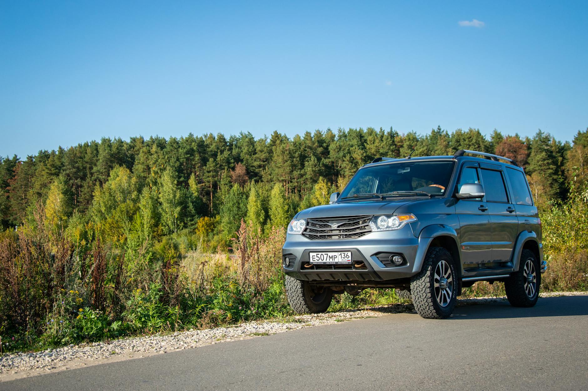 https://www.pexels.com/photo/silver-uaz-patriot-on-road-with-forest-behind-18382521/