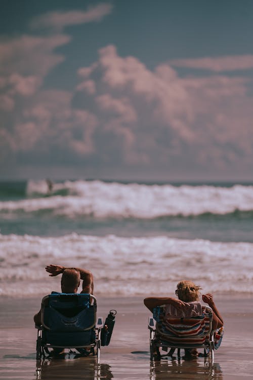 Free Two People on Sun Loungers on the Beach Stock Photo