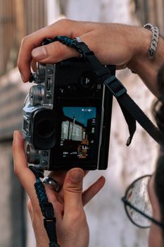 Hands holding a camera with building facade visible on screen for photography shot.