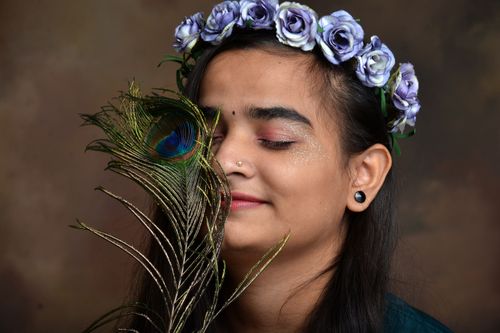 Free Artistic portrait of a woman with a peacock feather and floral wreath, eyes closed in serene expression. Stock Photo