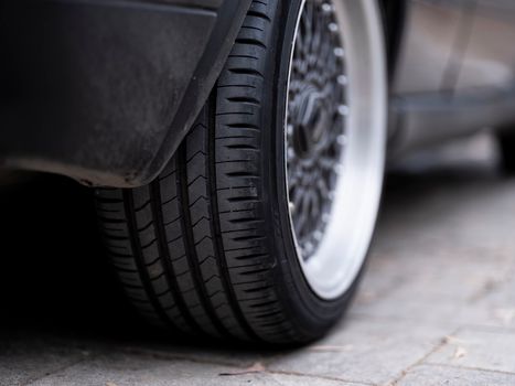 Detailed view of a car tire on urban pavement, showcasing tread and wheel design.