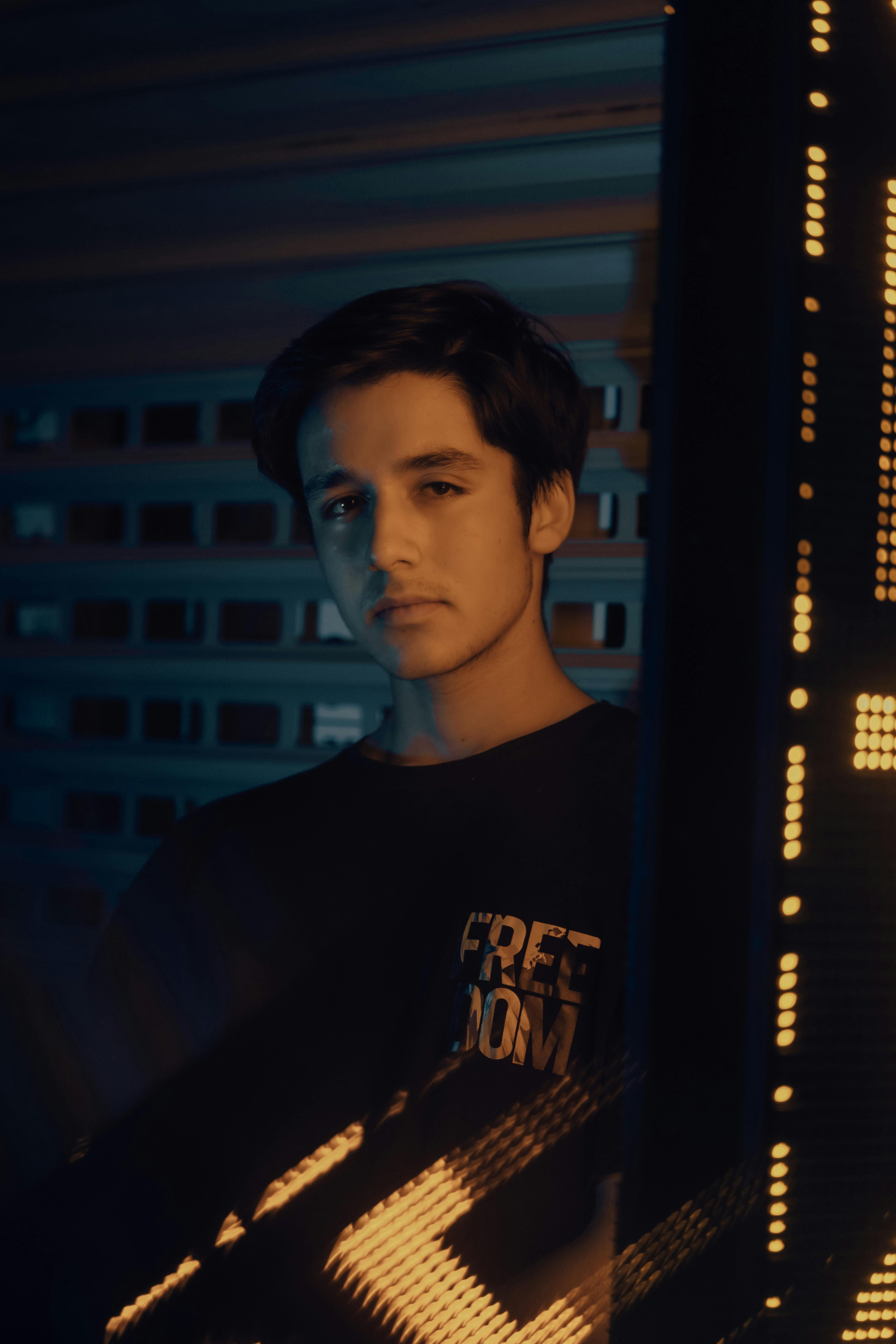 Young man in moody lighting with neon reflections, conveying introspection.