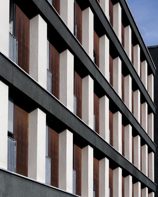 Closeup of a modern building facade featuring geometric patterns and windows in vertical perspective.