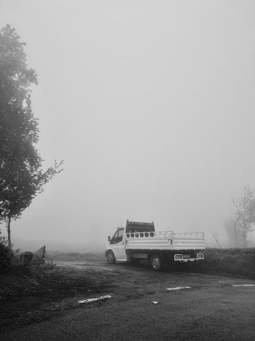 Truck on Dirt Road near Road under Fog