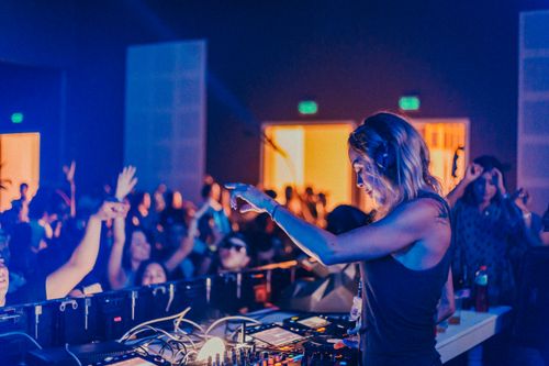Free Energetic scene of a female DJ playing music at a lively nightclub party. Stock Photo