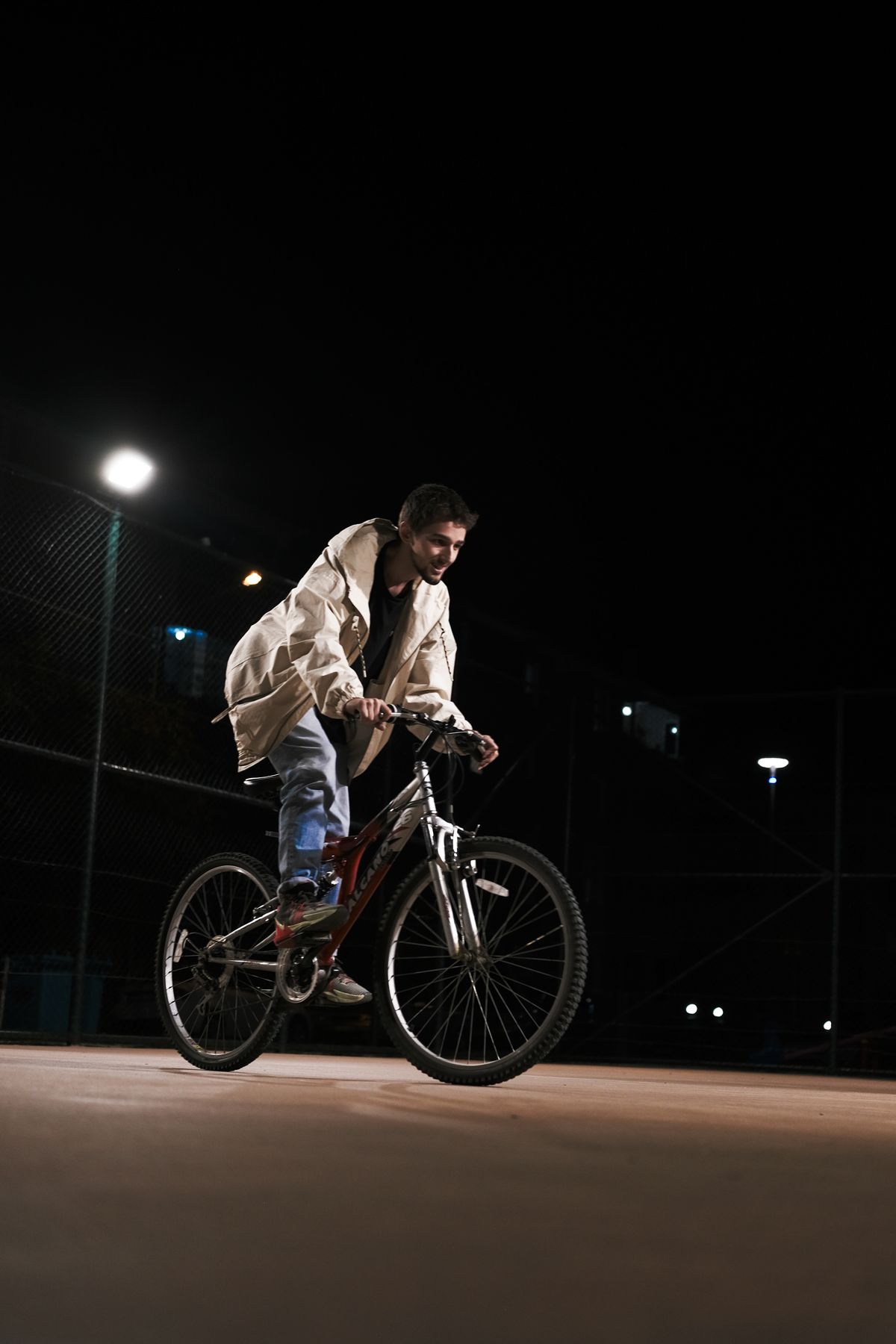 Person riding a bicycle along an illuminated city street at night