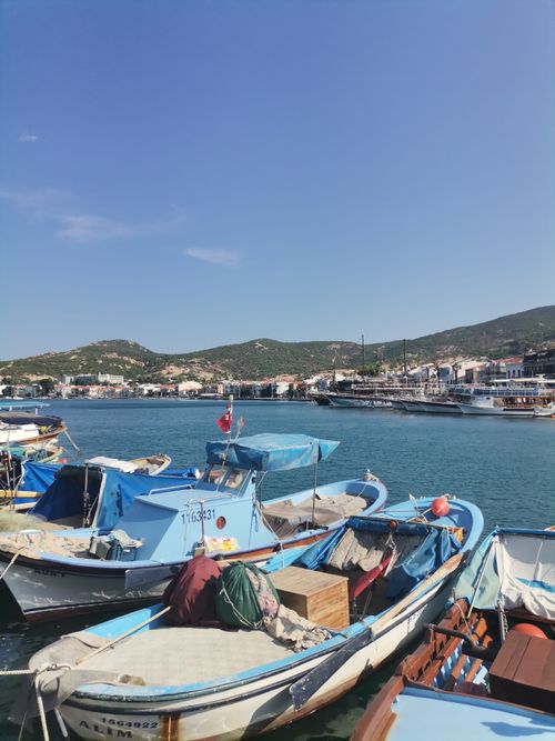 Free Charming coastal town harbor view with moored boats, clear blue sky, and distant hills. Stock Photo