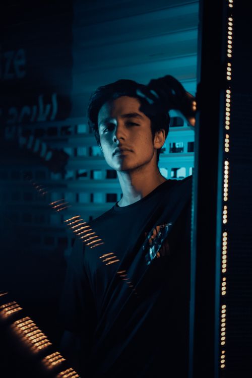 Free A man standing by a window with dramatic lighting, creating a moody nighttime portrait. Stock Photo