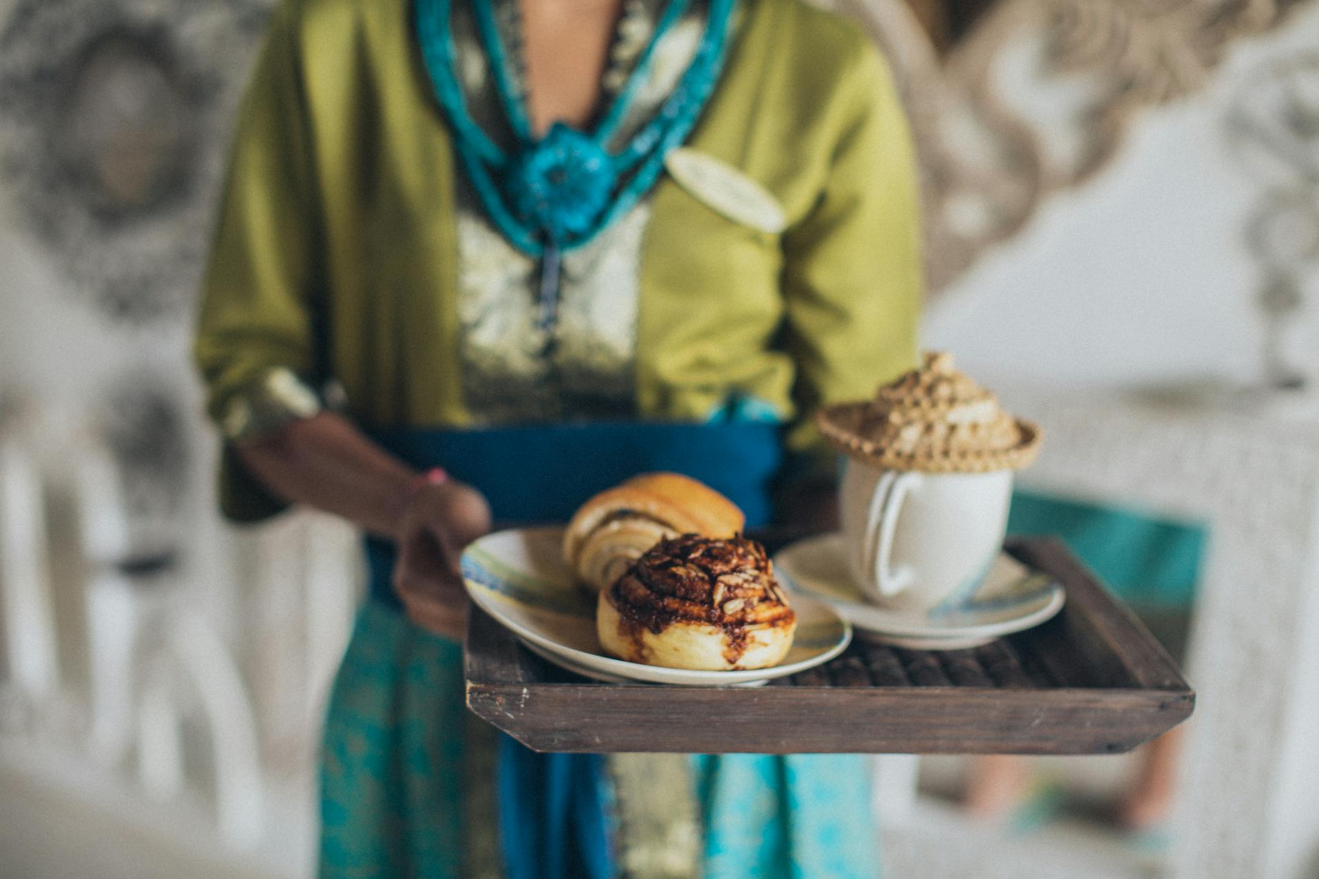 Woman Serving Plate of Cinnamon Breads and Cup of Beverage