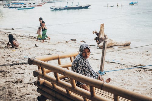 Woman Wearing Black Tops Sitting on Brown Bamboo Bench Near Sea
