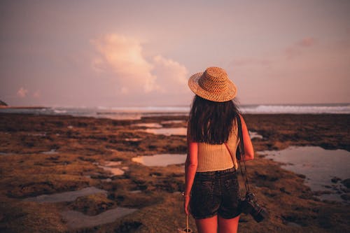 水域に面した海岸に立つ女性のセレクティブフォーカス写真