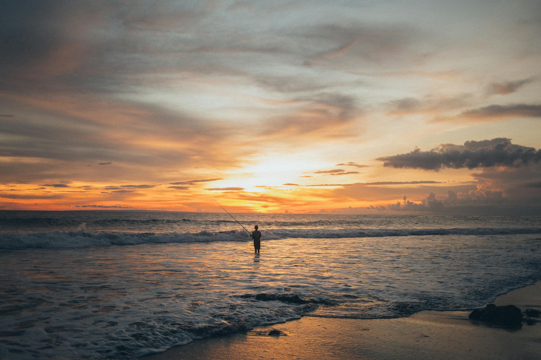 a person using a fishing rod to catch fish on a beach