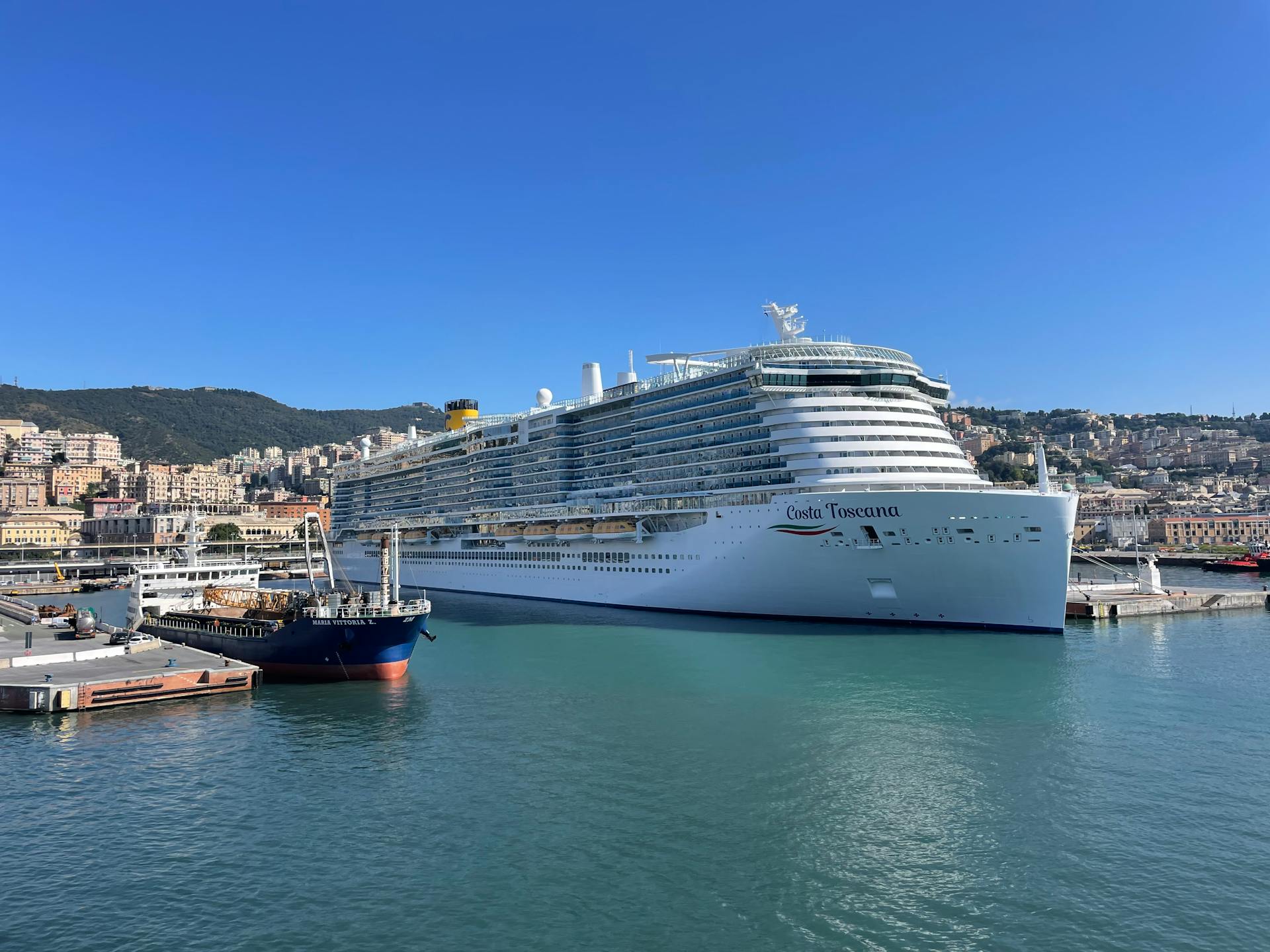 A luxurious cruise ship docked at a scenic coastal harbor on a sunny day, perfect for relaxation and travel enthusiasts.