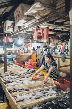 A woman selling fresh seafood at a vibrant and busy fish market.