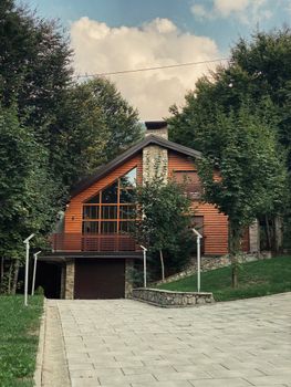 A contemporary wooden house with large windows nestled among trees, showcasing modern architecture.