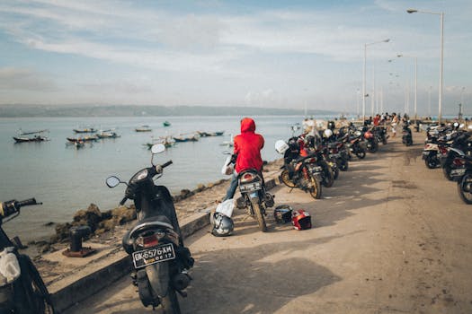 在海岸环境中，一名摩托车手坐在码头旁，自行车停在一旁