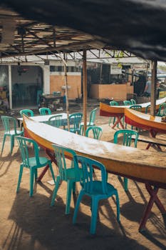 休闲户外市场的座位区，配有绿松石塑料椅子和置于阴凉处的木桌