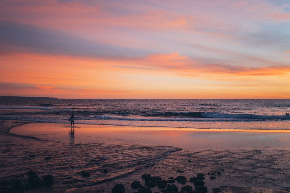 A tranquil beach scene at sunset with silhouettes in the distance capturing the beauty of nature.