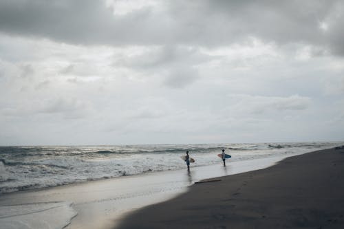 免費 站在海灘上的兩個衝浪者 圖庫相片