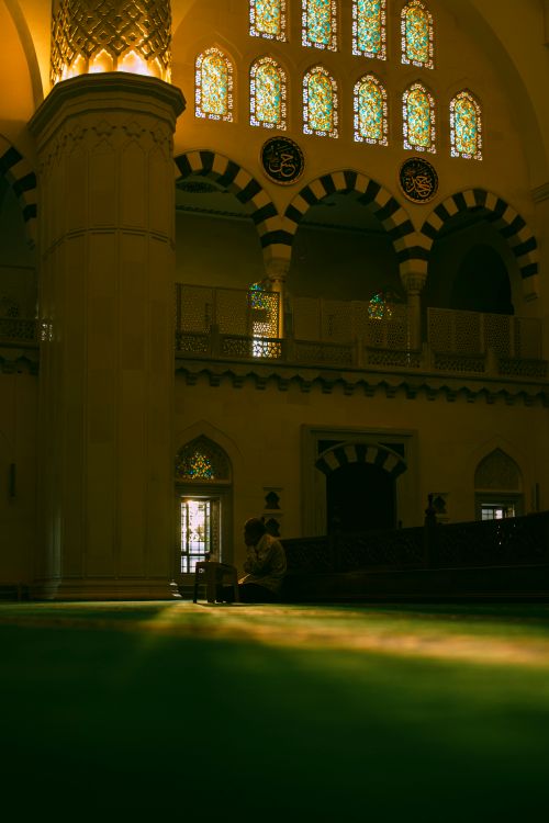 Free Dimly lit mosque interior with intricate stained glass windows and traditional architecture. Stock Photo