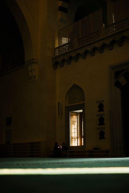 Free A dimly lit interior of a traditional mosque with intricate architecture under night lighting. Stock Photo