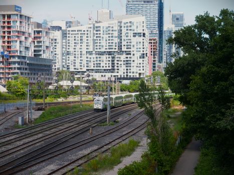 View of a train passing through Toronto's urban skyline and greenery, highlighting city transport.