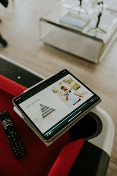 Tablet on a pool table showing a presentation, with a remote nearby. Indoor setting.