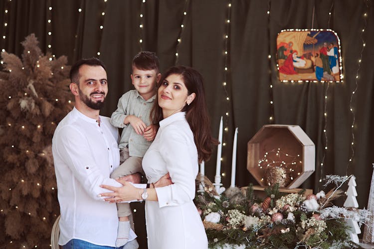 Family With A Child Posing With Christmas Decoration And A Nativity Scene